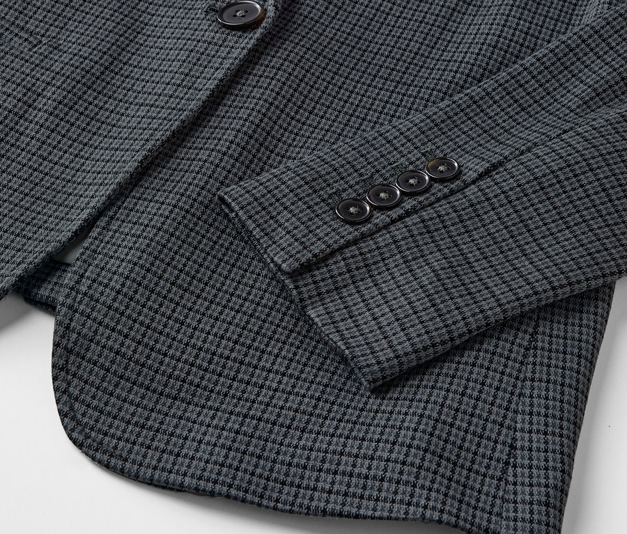 Détail d'un blazer gris avec un motif fin et des boutons sur la manche.