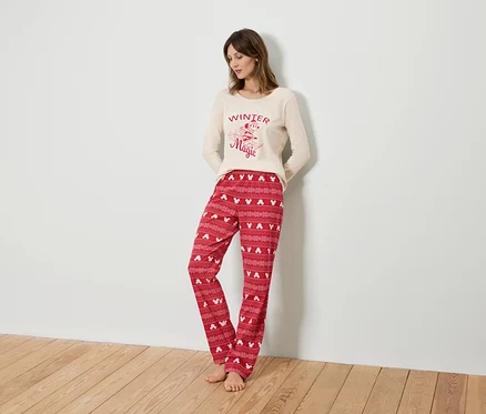 Femme portant un haut de pyjama beige à manches longues et un pantalon de pyjama rouge avec Mickey Mouse.