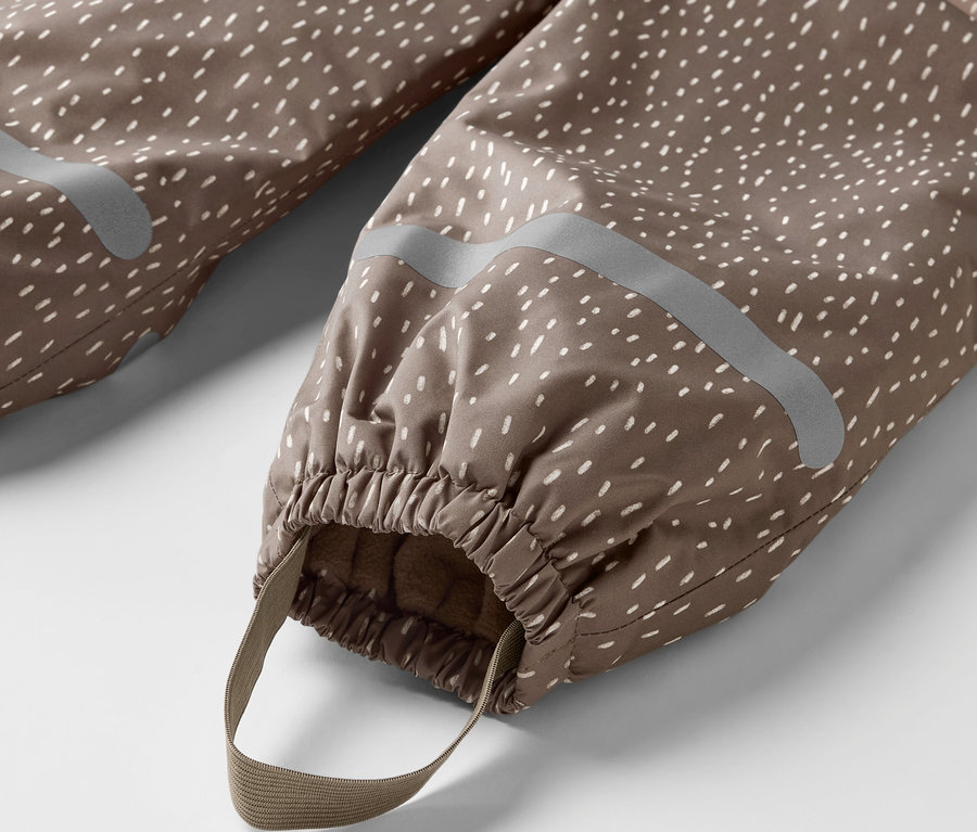 Détail d'un pantalon de pluie thermique pour enfant, ours, marron avec des points blancs, avec élastique et bande.