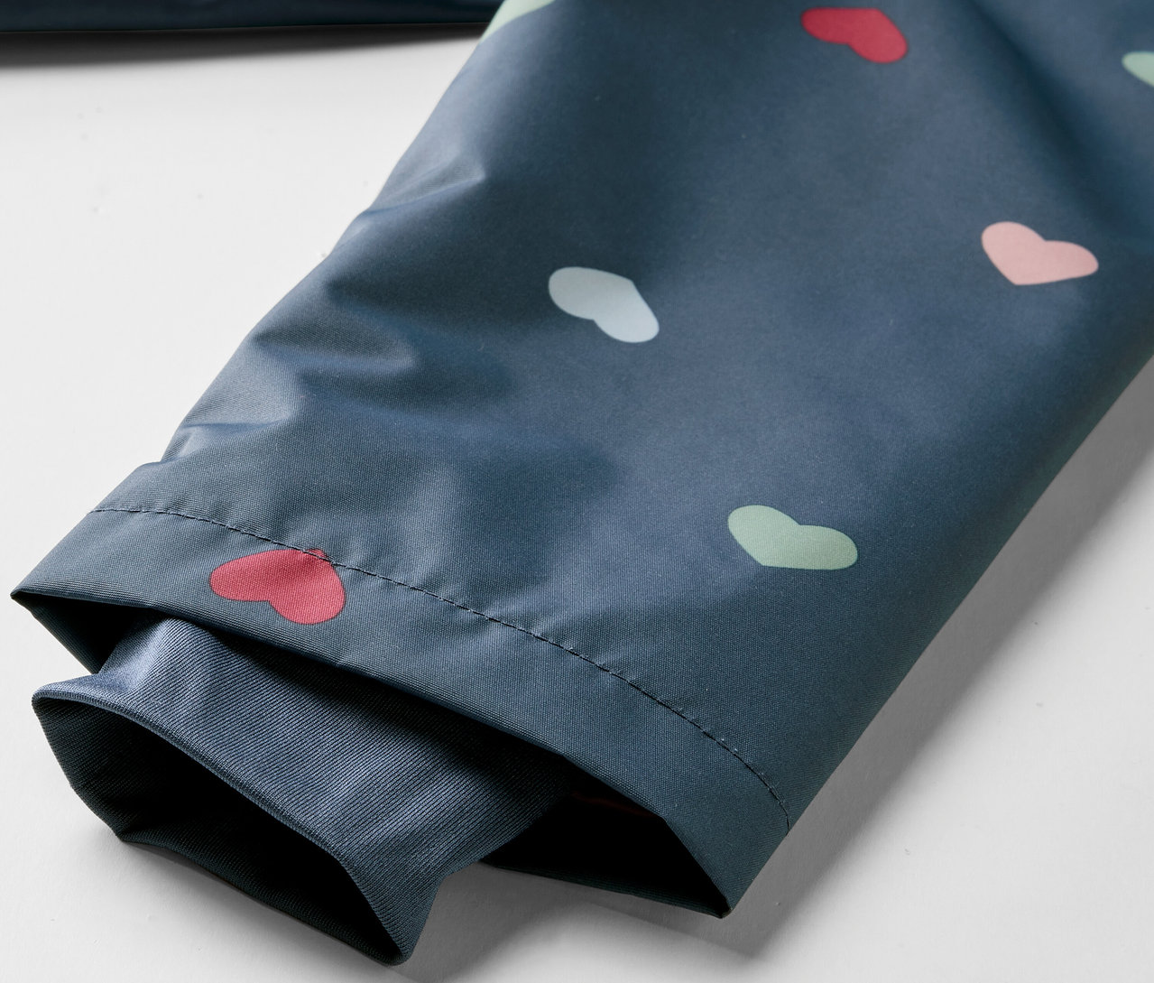 Détail d'une veste imperméable thermique pour enfants avec un motif de cœurs.