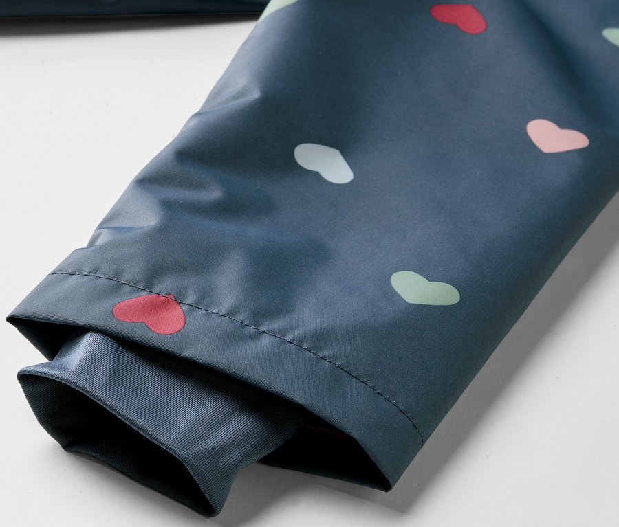 Détail d'une veste imperméable thermique pour enfants avec un motif de cœurs.