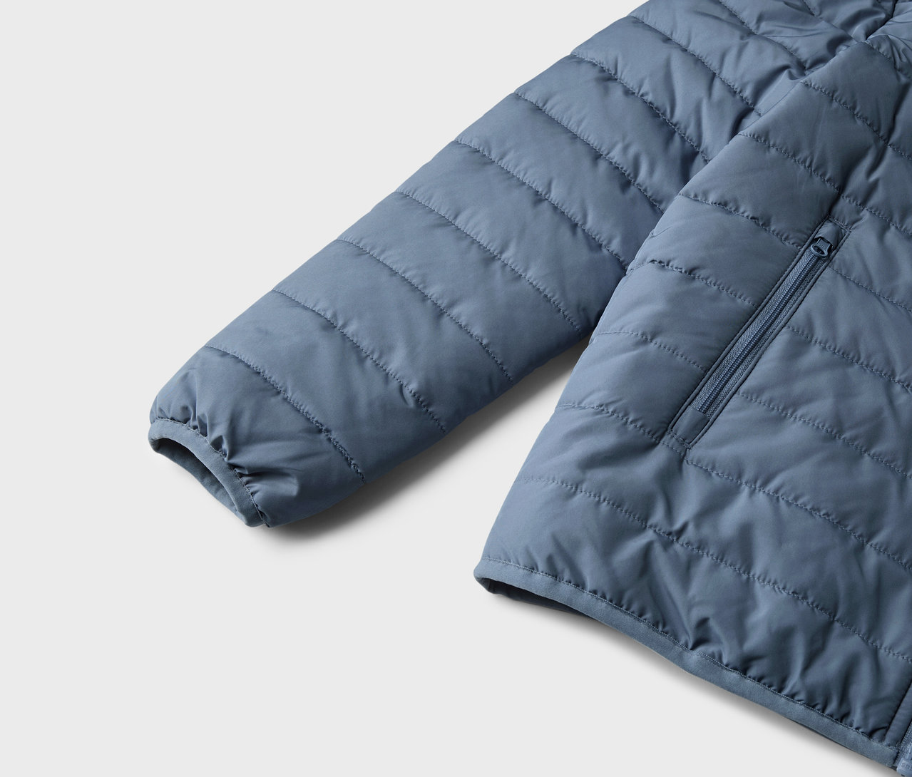 Détail d'une veste matelassée bleue pour enfants.