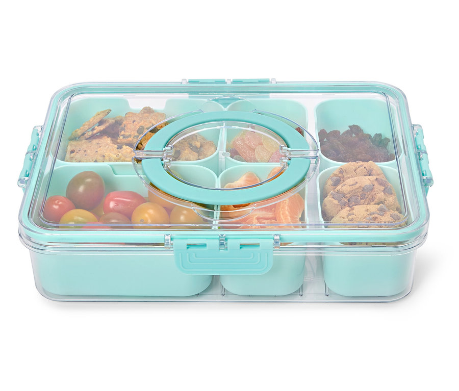 Boîte à lunch bleu clair avec couvercle transparent et diverses collations telles que des biscuits, des tomates et des mandarines.