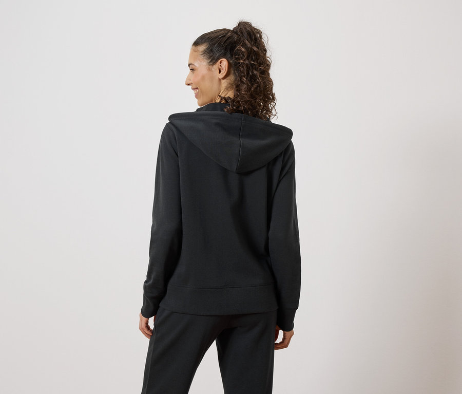 Femme vue de dos portant un sweat à capuche noir et un pantalon de jogging.