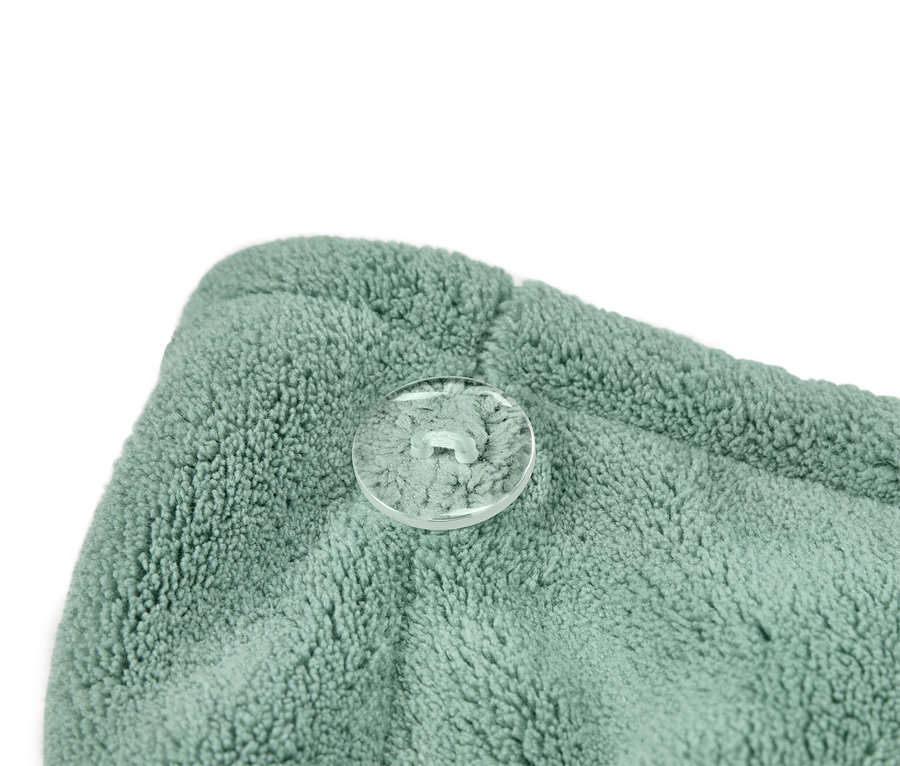 Gros plan d'un turban de serviette turquoise et vert avec un bouton transparent.