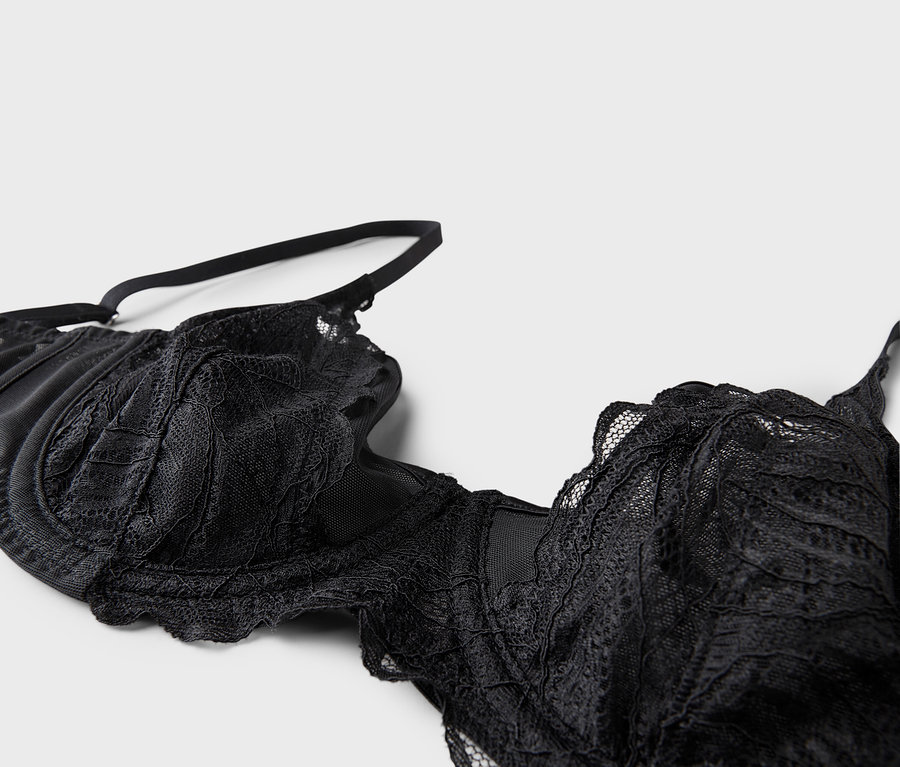 Gros plan d'un soutien-gorge noir en dentelle avec bretelles réglables sur fond blanc.