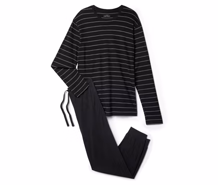 Un pyjama noir rayé est posé sur un fond blanc.