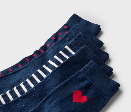 Cinq chaussettes bleu marine superposées avec des cœurs rouges, des rayures blanches, des pois blancs et un seul cœur rouge.