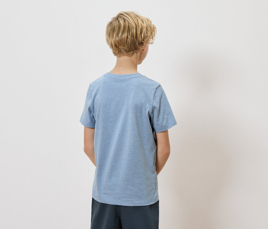 Vue arrière d'un enfant aux cheveux blonds et bouclés, portant un t-shirt bleu clair et un short bleu marine sur fond blanc.