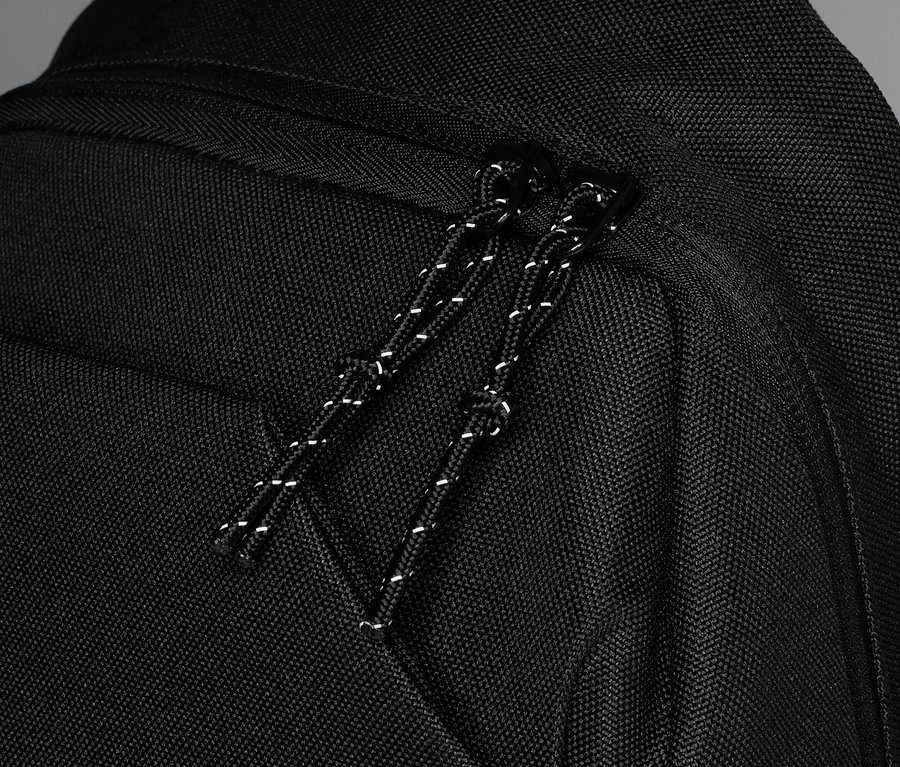 Gros plan sur un sac à dos noir avec fermeture éclair et cordon de serrage.