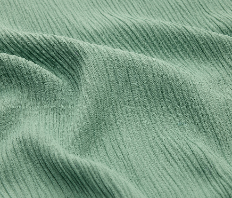 Gros plan d'un tissu côtelé vert menthe avec des plis.