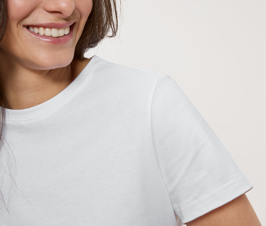 Gros plan d'une femme souriante portant un t-shirt blanc.