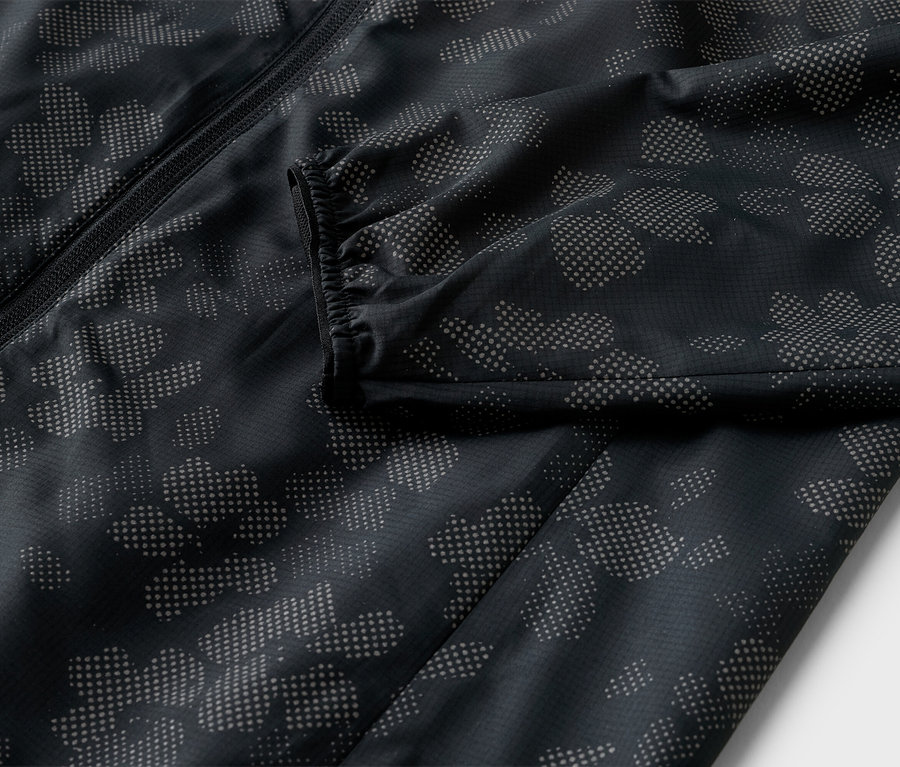 Gros plan d'une veste noire avec fermeture éclair et motif de fleurs pointillées.