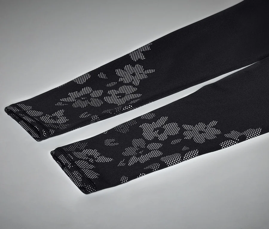 Gros plan de deux leggings noirs à motif floral sur fond gris.