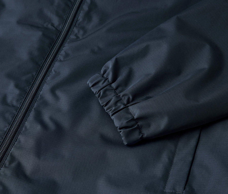 Gros plan sur une veste bleu marine avec une fermeture éclair et des poignets élastiques.