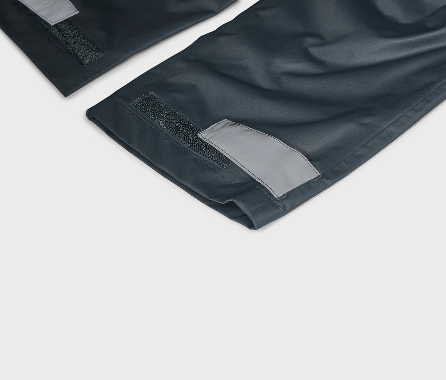 Vue détaillée de jambes de pantalon bleu marine avec fermeture velcro et détails réfléchissants sur les ourlets.