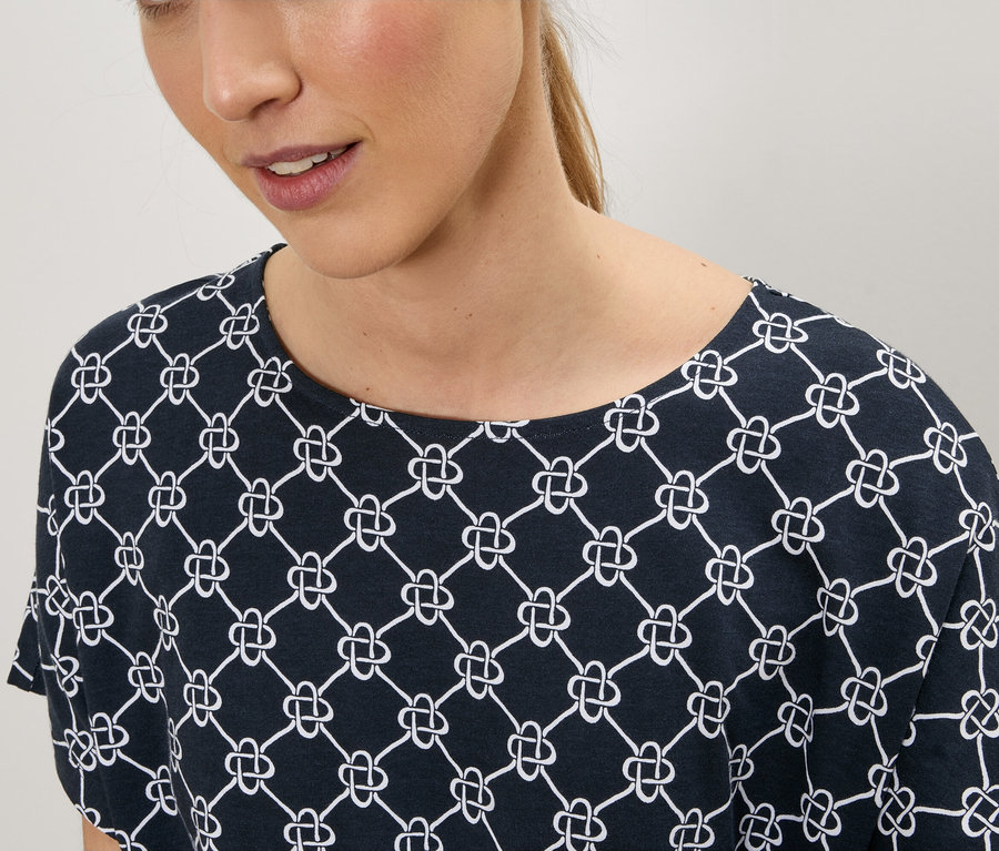 Femme portant un t-shirt bleu marine avec un motif de nœuds blancs.