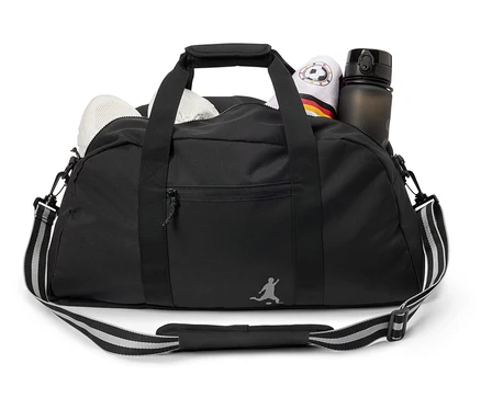 Sac de sport noir avec des chaussures blanches, une serviette sur le thème de l'Allemagne et une bouteille d'eau.
