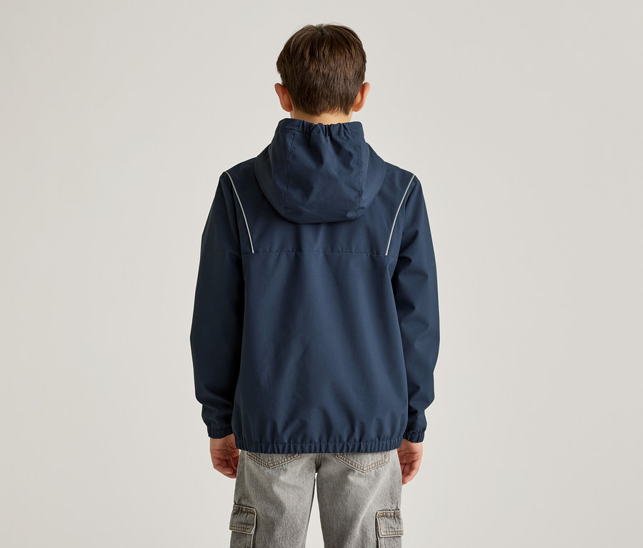 Vue arrière d'un garçon portant une veste à capuche bleu marine avec des rayures blanches et un pantalon cargo gris sur un fond clair.