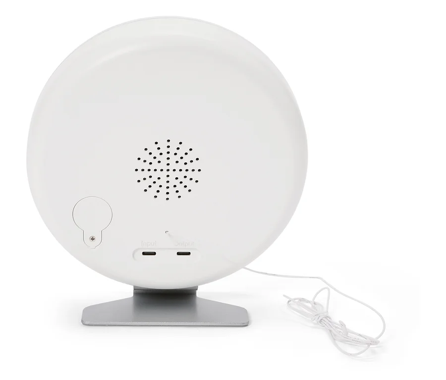 Arrière d'une lampe ronde blanche sur un socle argenté avec haut-parleur, ports d'entrée et de sortie et un câble blanc.