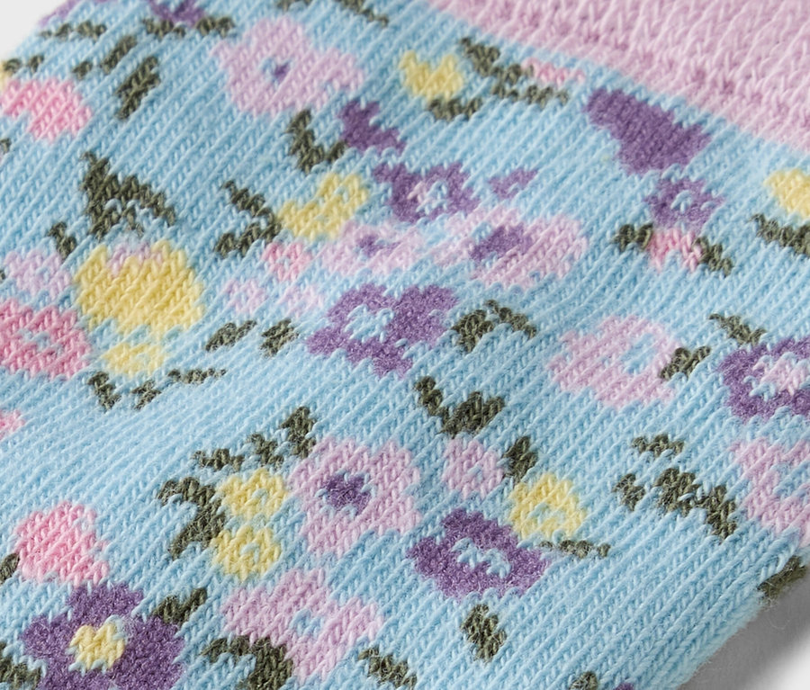 Gros plan d'une chaussette bleu clair avec un motif floral jaune, violet et rose.