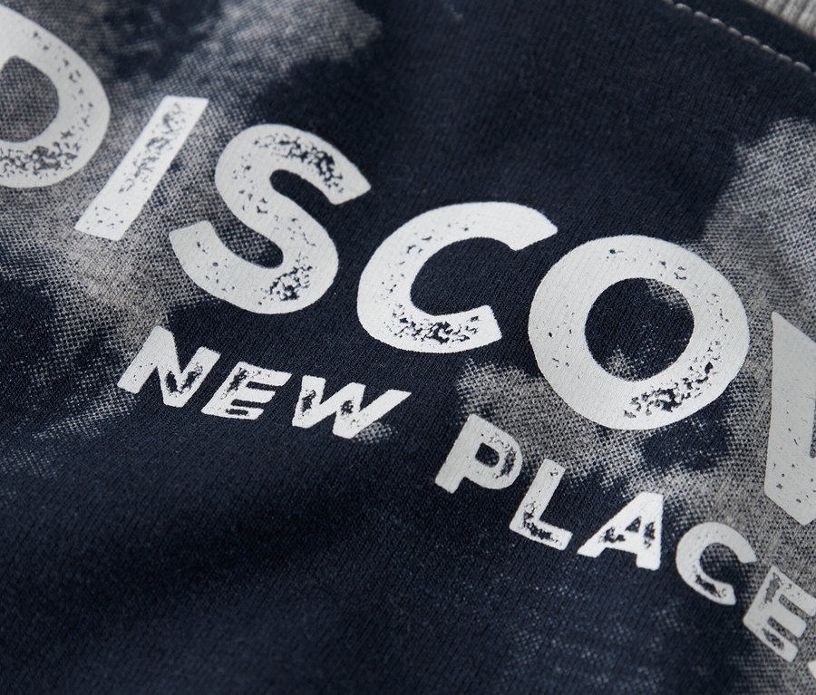 Gros plan d'un tissu bleu marine avec l'inscription "DISCOVER NEW PLACES".