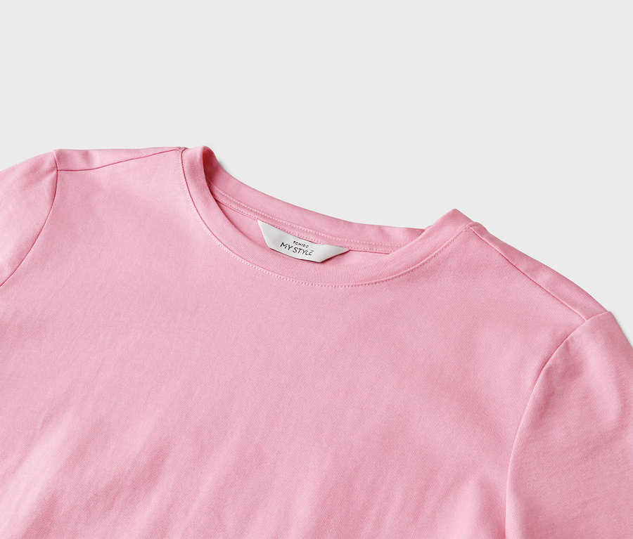 Gros plan d'un t-shirt rose clair à col rond avec une étiquette blanche portant l'inscription « Tchibo My Style ».