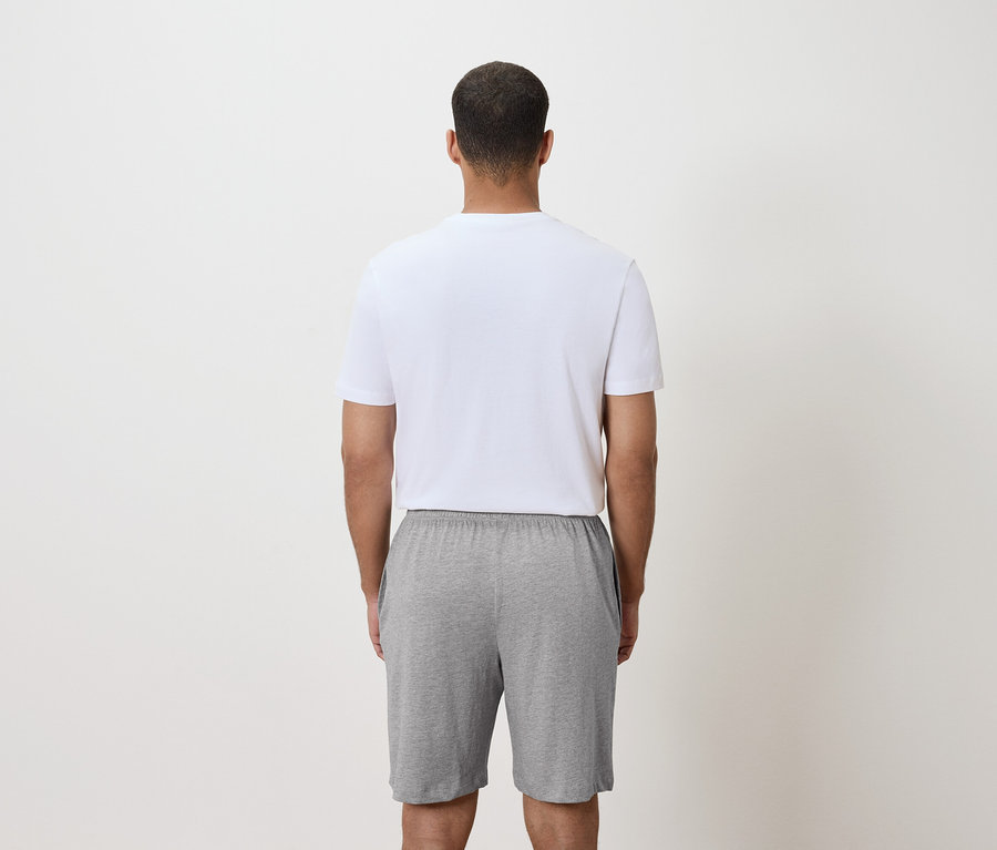 Vue arrière d'un homme portant un t-shirt blanc et un short gris.