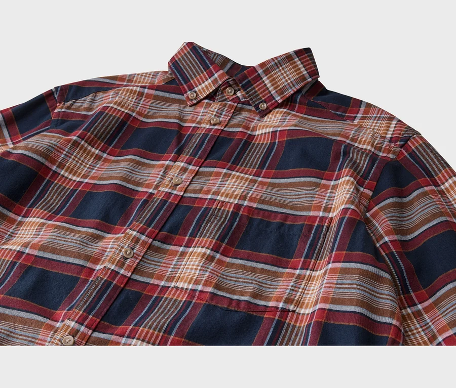 Chemise à carreaux bleu marine, rouge, marron et blanc, avec un col boutonné, des boutons sur le devant et une poche poitrine.