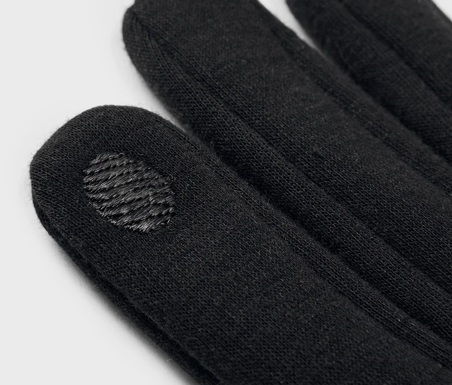 Gros plan de gants noirs, montrant les bouts des doigts, l'un d'eux avec une zone texturée pour écrans tactiles.