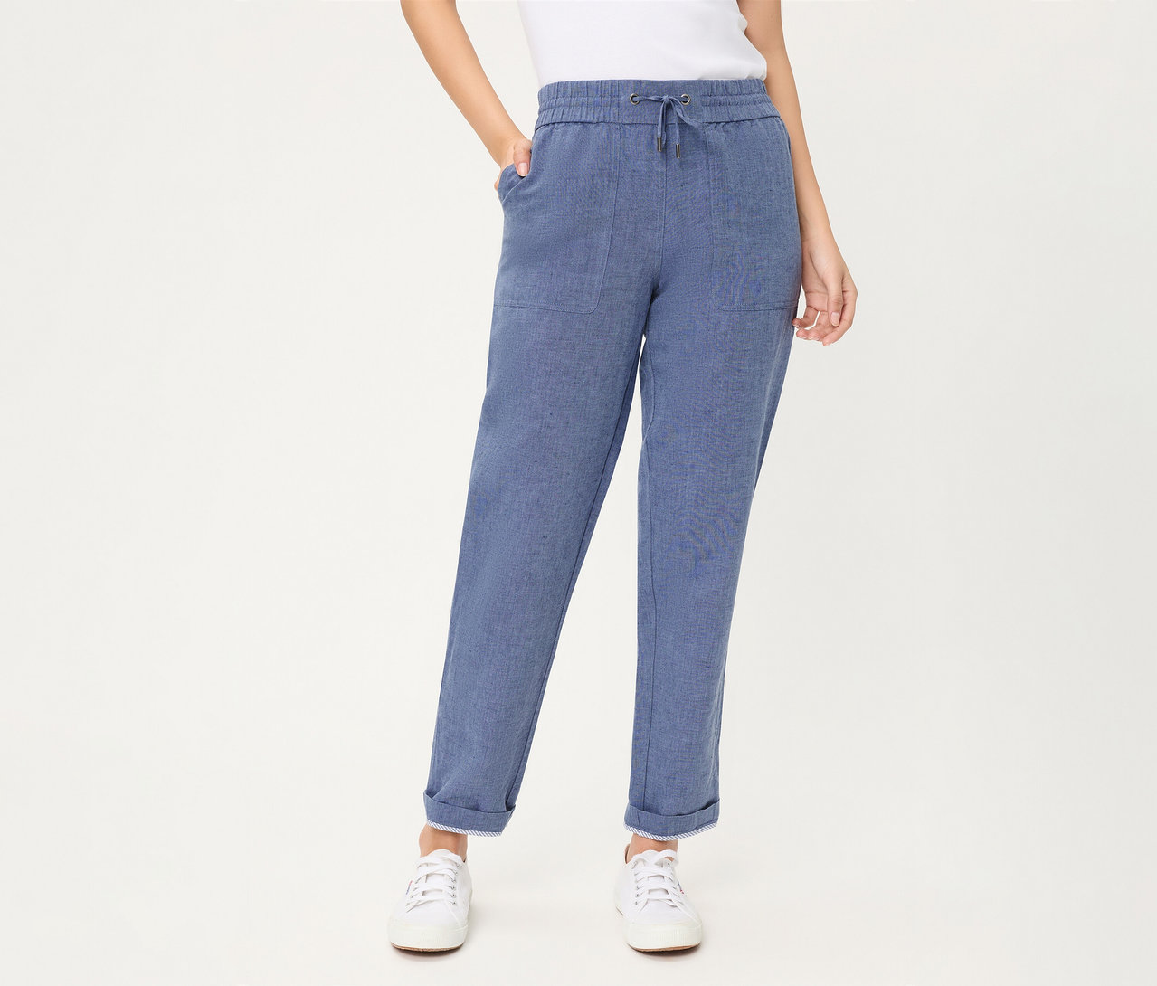 Personne portant un jean Olsen cropped bleu avec cordon de serrage, poches plaquées et revers aux chevilles, associé à des baskets blanches.