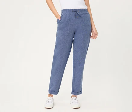 Personne portant un jean Olsen cropped bleu avec cordon de serrage, poches plaquées et revers aux chevilles, associé à des baskets blanches.