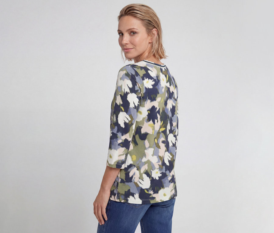 Femme portant un T-shirt 3/4 Olsen à motif floral marine, vert et blanc, regardant par-dessus son épaule.