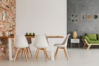 Un salon meublé de façon moderne avec une table à manger qui comporte des chaises coque en résine de couleur blanc avec des pieds en bois clair.