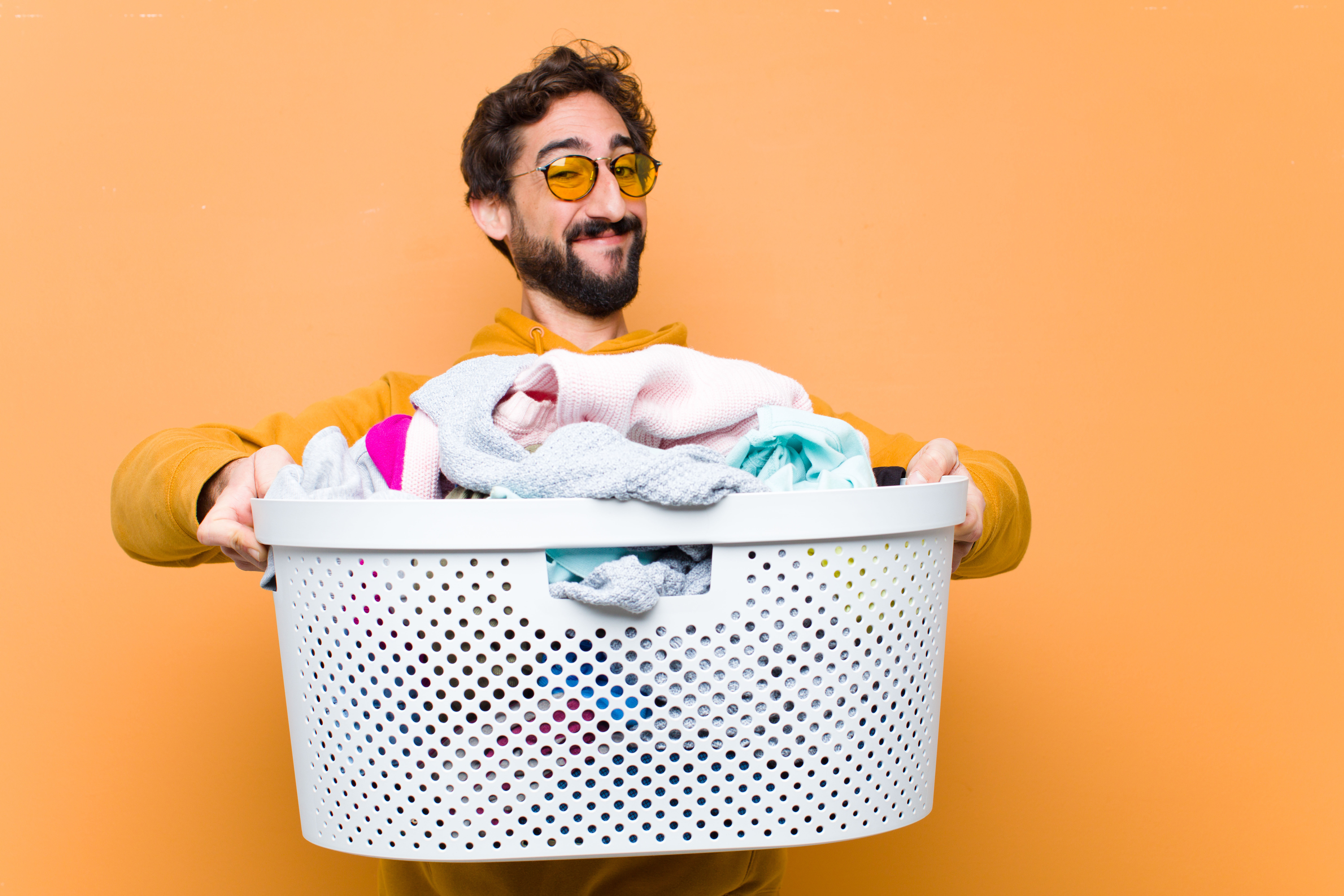 Homme qui rit avec un panier à linge rempli.