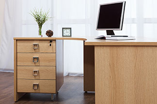 Une alternative peu encombrante à l’armoire de bureau : bureau avec élément bas à tiroirs et un compartiment verrouillable.
