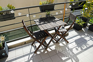 Chaises de jardin pour le balcon : sur un petit balcon, il y a deux chaises en bois et une table carrée en bois.