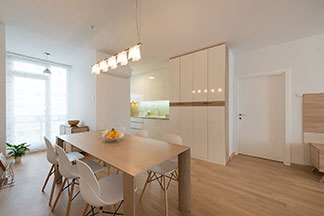 Le plafonnier parfait pour la cuisine : une cuisine lumineuse avec une table rectangulaire en bois au-dessus de laquelle est suspendu un plafonnier avec cinq spots individuels.