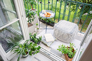 Un miracle d'espace : Un petit balcon avec un sac de haricots et des plantes vertes sur lequel se trouve une petite table de jardin ronde.