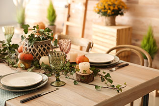 Décorez de façon saisonnière : une décoration automnale avec des petites citrouilles et vrilles de lierre orne une table dressée.