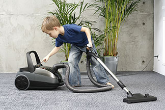 La sécurité grâce à la bonne qualité : un petit garçon utilise un aspirateur.