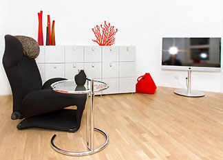 Les tables d'appoint ne sont pas seulement pratiques : un salon avec un buffet blanc, un fauteuil noir, une télévision et une table d'appoint ronde.