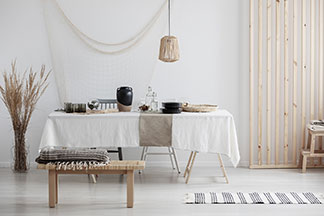 Une table à manger avec une nappe en lin. La table et le salon ont un style rustique naturel, auquel ce tissu convient parfaitement.