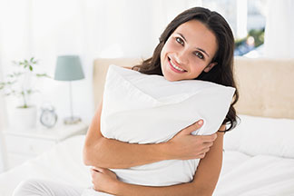 Pas de souci de polluants : une femme aux cheveux bruns tient dans ses bras un oreiller blanc rectangulaire.