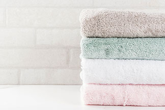 Linges de bain essentiels : serviettes en éponge de coton empilées, propres et colorées.