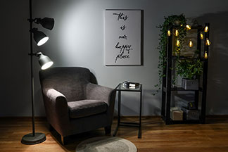 Un classique parmi les fauteuils : un fauteuil club sombre avec une petite table d'appoint et un lampadaire noir dans le salon.