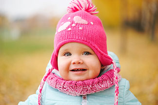 Sur un pont dans un parc d'hiver, une jeune mère tient son fils heureux dans un habit de neige, un chapeau, une écharpe et des gants