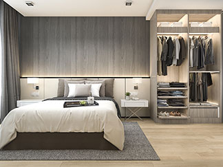 Bonne qualité pour la garde-robe de votre chambre : vue sur une chambre à coucher avec le lit à gauche et une armoire de chambre ouverte en bois gris vitrifié à droite.