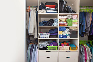 Des aides pour le rangement dans l'armoire : vue sur une armoire ouverte, très bien structurée grâce à des systèmes d'accrochage, des tiroirs, des boîtes et des coffrets divers.