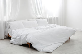 La bonne taille pour se sentir bien : une chambre lumineuse avec un lit double sur lequel se trouve une grande couette.